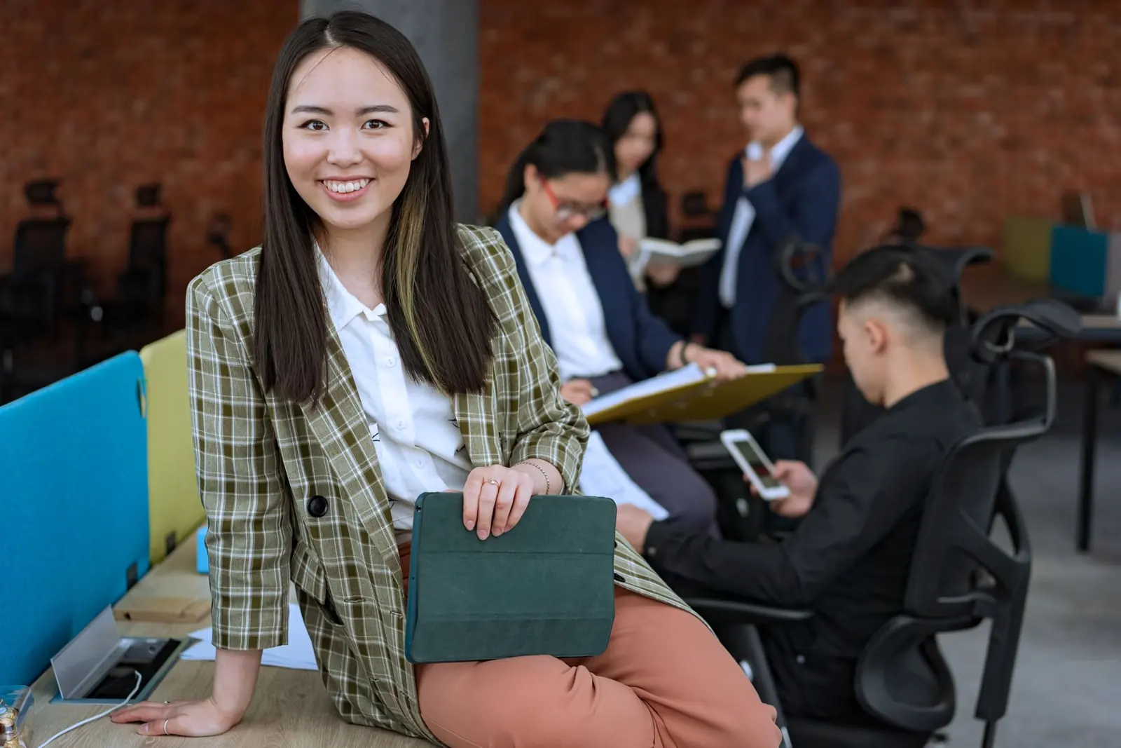 Smiling young woman in a modern office, with her team working behind her