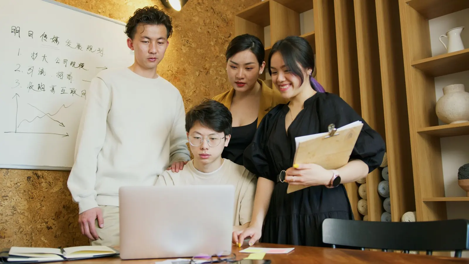 Young team gathered around a laptop, planning a project together