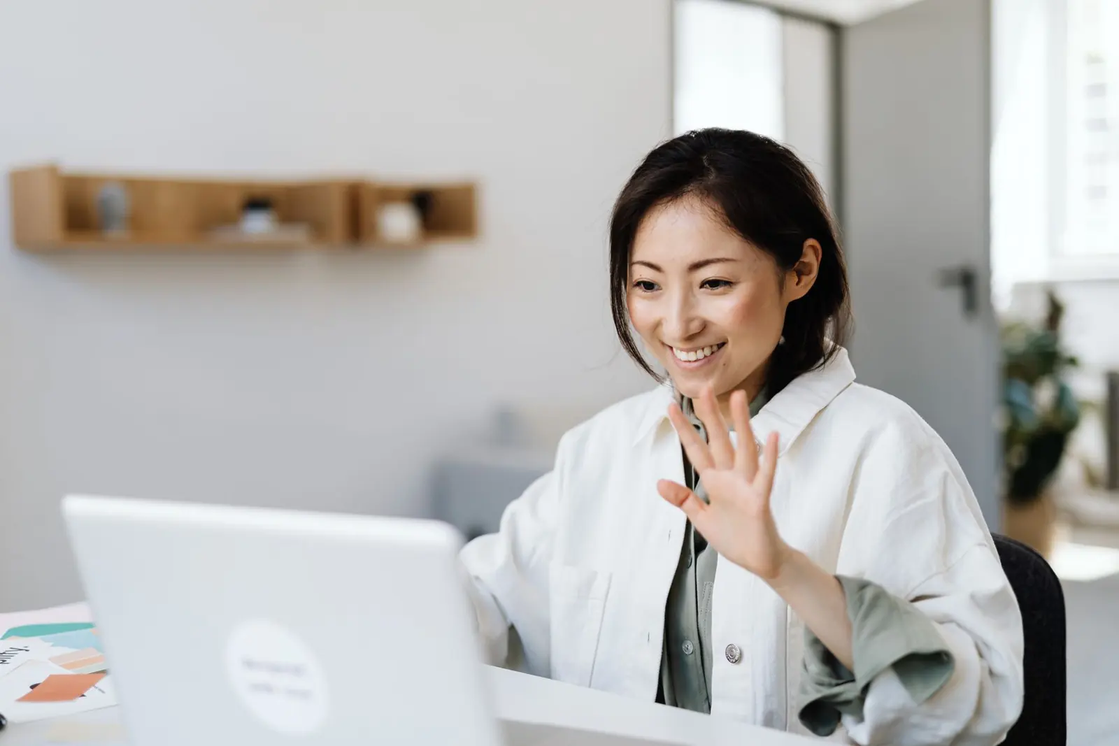 Smiling young woman waving to her class on a video call