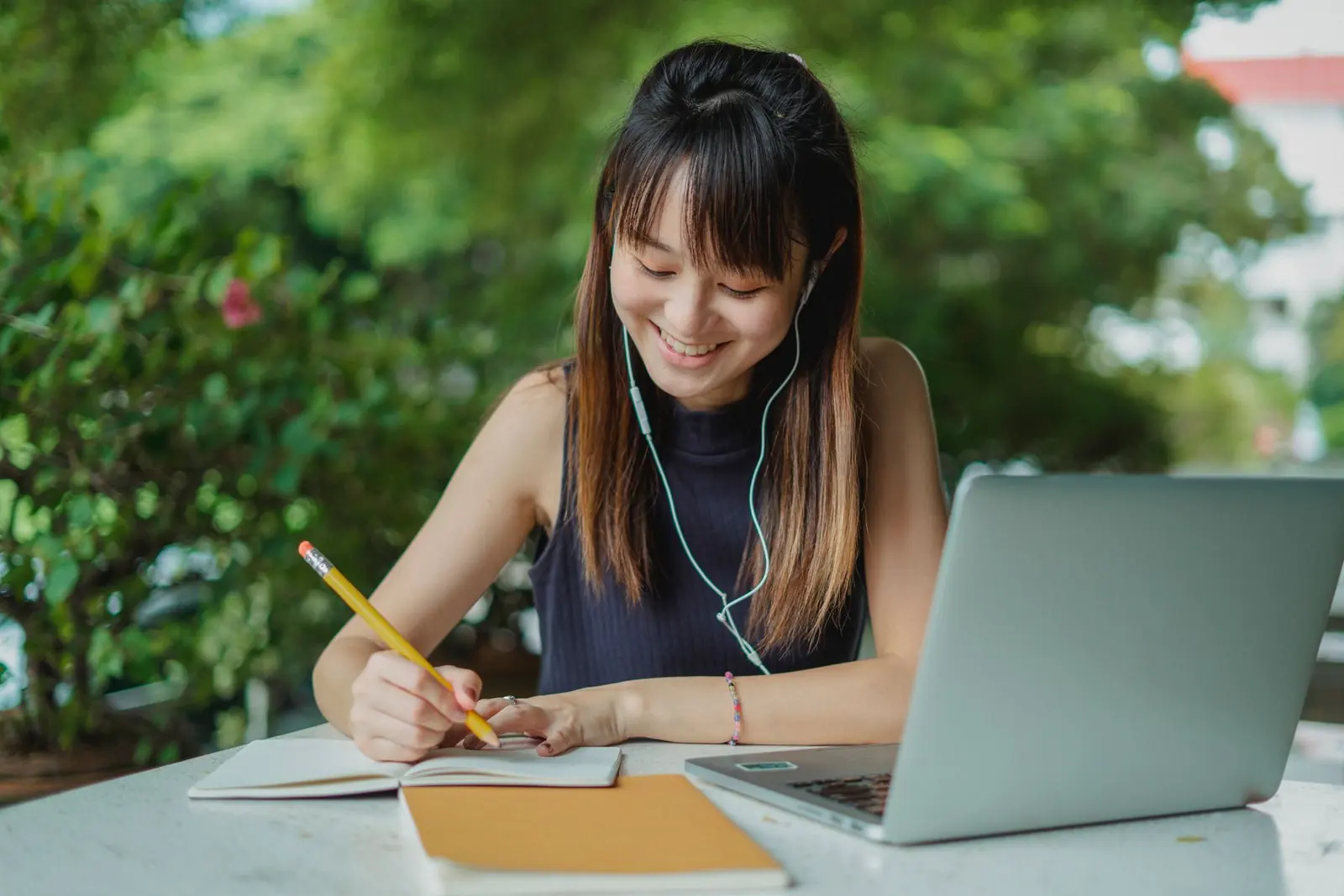 Student with earphones taking notes during an online class