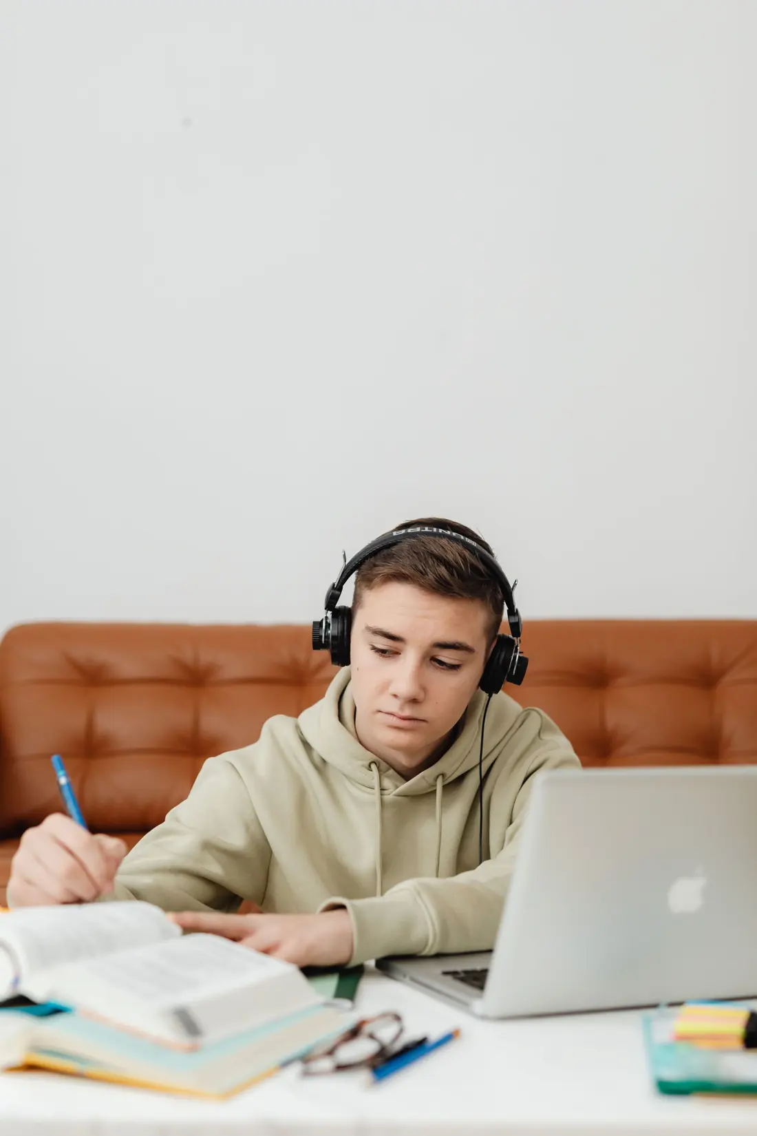 Teenage boy with headphones studying English at home