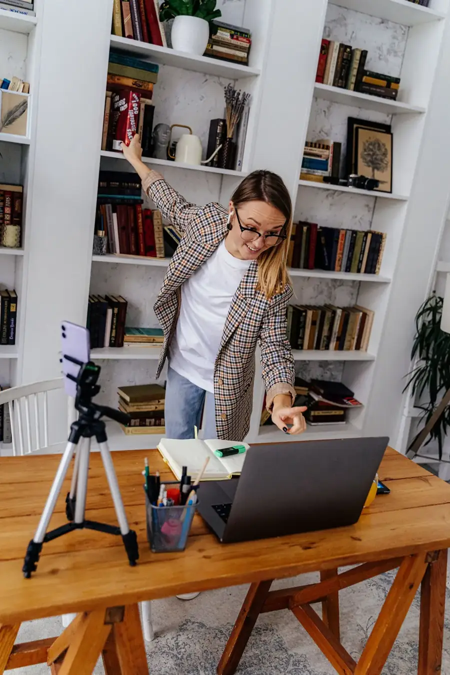 Teacher leading an online English class from her desk, with a camera on a tripod