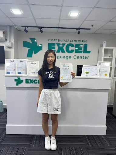 Student proudly holding certificate at Excel Language Center